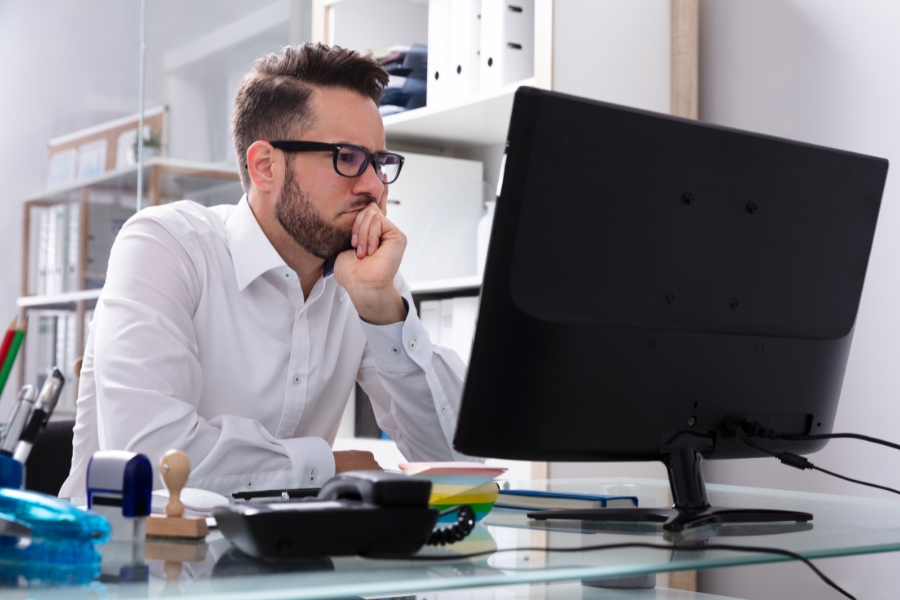 אדם יושב מרוכז מול מסך מחשב.