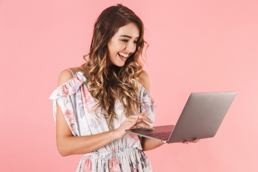 אישה מחזיקה לפטופ בעמידה.